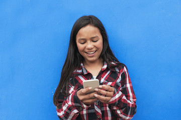 Portrait of cute latino girl using the mobile in the street.