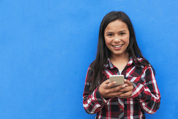Portrait of cute latino girl using the mobile in the street.