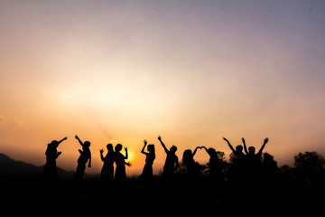 Fototapeta na wymiar Silhouette of cheering young generation Stand on the mountain at sunset.,Business concept idea
