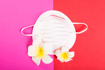 One face mask on pink and red background with exotic flowers.