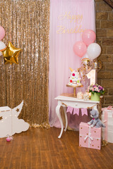 Children's photo zone with sweets and a balloons. Decorations for a One year old Girl’s Birthday party. Concept of children's birthday party.
