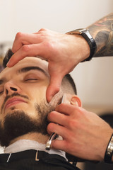 Obraz na płótnie Canvas Client during beard shaving in barber shop