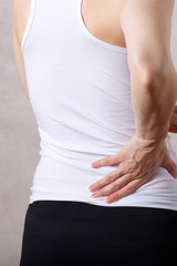 Young caucasian lady has a pain in her back Closeup