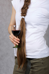 Young lady dressed in jeans keeps a glass of red wine. Closeup