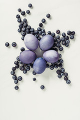 top view of purple easter eggs and blueberries on grey