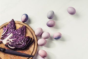 Obraz na płótnie Canvas top view of violet painted eggs and purple cabbage with knife on wooden cutting board on grey