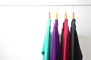 Multi colored female shirts with striped on hangers against a white background