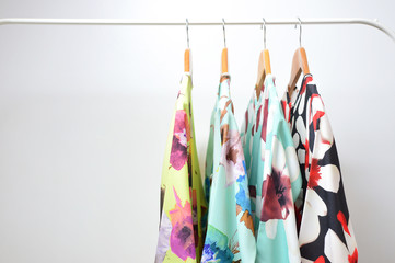clothes of different pattern on wooden hangers on isolated white background