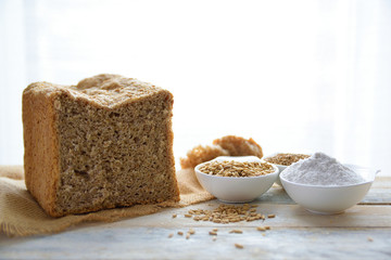 Wholemeal bread on a burlap fabric next to some flour and cereals against a white background. Empty copy space for Editor's text.