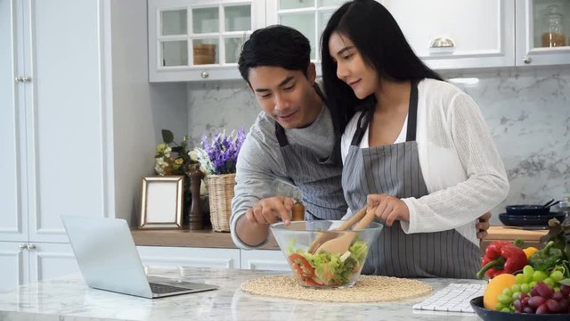 The happy couple use laptop computer while cooking in kitchen