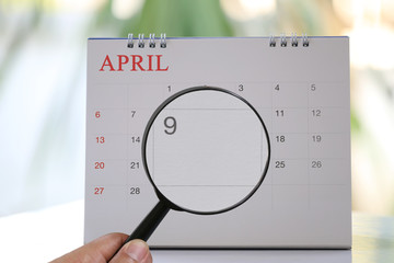 Magnifying glass in hand on calendar you can look ninth day of month,Focus number nine in April.