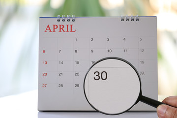 Magnifying glass in hand on calendar you can look Thirty day of month,Focus number thirty in April.
