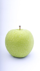 Closeup of green apple with water drops on white background. Selective focus.