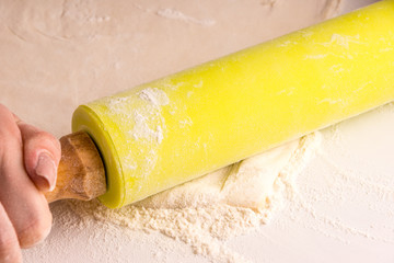 Woman rolls puff pastry on a light table, floured