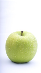 Closeup of green apple with water drops on white background. Selective focus.