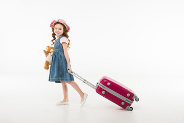 Little stylish child with teddy bear and suitcase isolated on white, travel concept