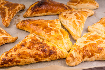 Delicious golden triangles of puff pastry on baking paper close-up