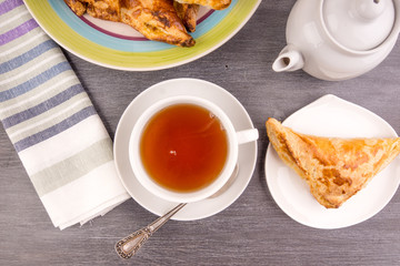 Delicious golden triangles of puff pastry on the table and a cup of tea - top view