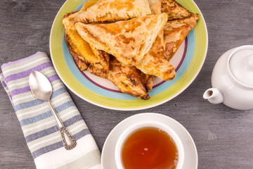 Delicious golden triangles of puff pastry on the table and a cup of tea - top view