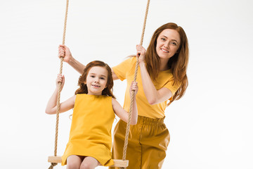 Mother riding little daughter on swing isolated on white