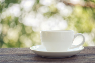 White coffee cup is placed on a brown wooden floor.
