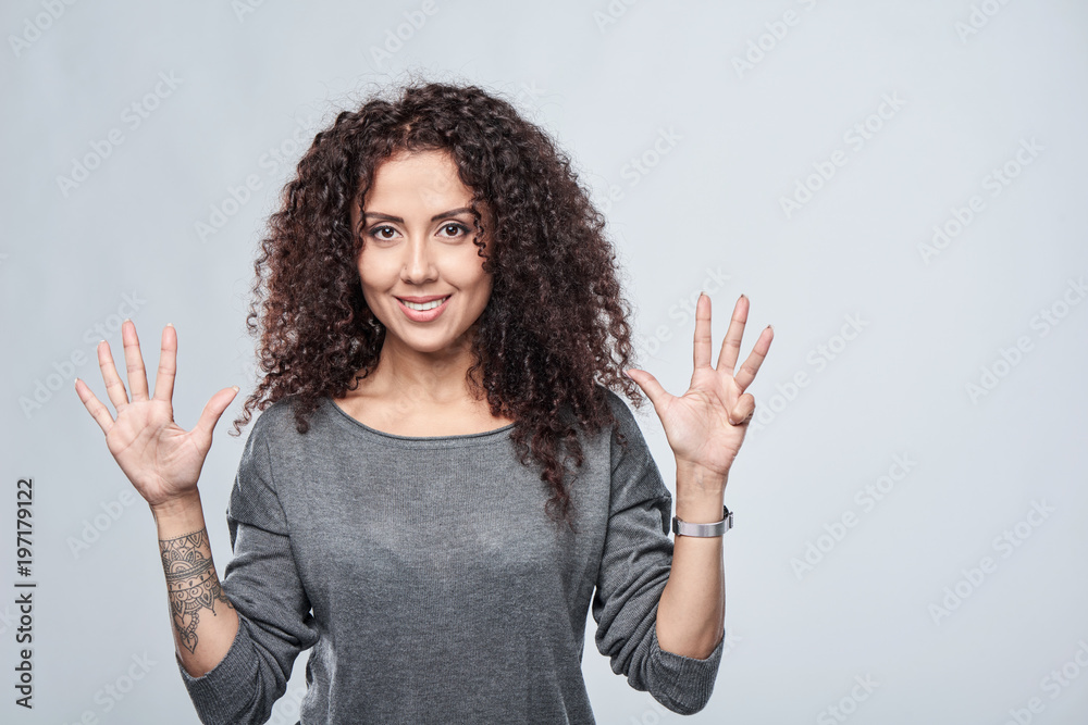 Wall mural Hand counting - nine fingers. Smiling woman showing nine fingers