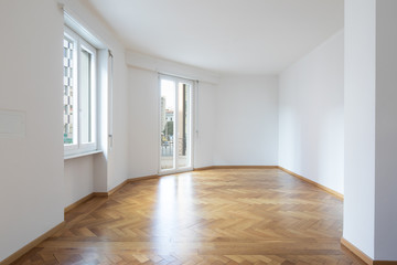 Empty room in a apartment with white walls and wooden floors