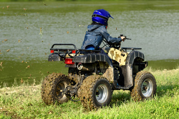 The boy is traveling on an ATV.