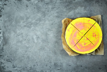sliced mousse cake with yellow red glaze on the gray concrete background