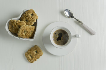 a cup of coffee with a spoon and biscuits