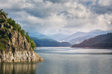 Naklejka na ściany i meble Panorama of a mountain lake Near the dam. Beautiful blue sky with clouds