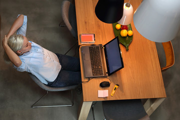 Praca na komputerze. Młoda kobieta siedzi przy stole w salonie i pracuje na laptopie 