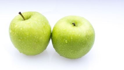 Closeup of green apple with water drops on white background. Selective focus.