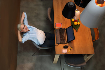 Praca zdalna na komputerze.
Młoda kobieta siedzi przy stole w salonie i pracuje na laptopie 
