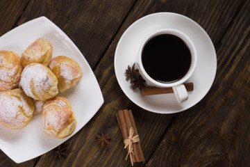 Delicious eclairs sprinkled with icing sugar, stand on a wooden table. Copy spase.