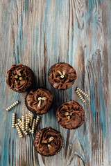 Five cupcakes decorated with whipped cream on a brown-blue wooden background