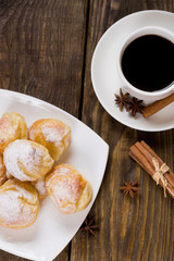 Delicious eclairs sprinkled with icing sugar, stand on a wooden table. Copy spase.