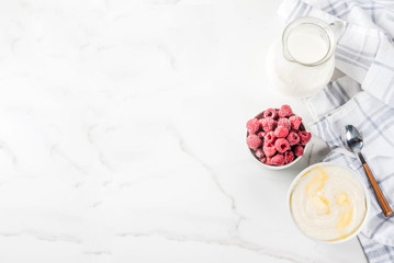 Healthy breakfast, semolina porridge with milk and raspberry, white marble table copy space