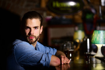 Bearded man drink alcohol on blurred bar background.