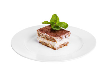 Rectangular piece of Tiramisu with a sprig of mint on a white plate. isolated on white background. Dessert for a menu in a cafe, restaurant, coffee shop side view