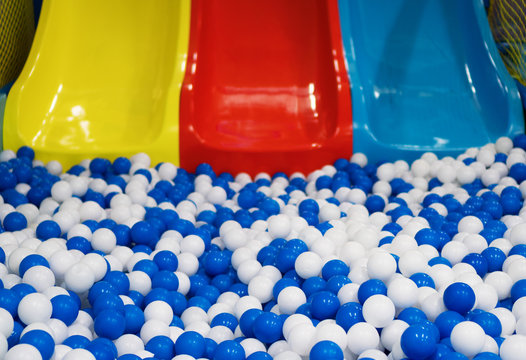 Plastic balls and colorful slides in playroom.