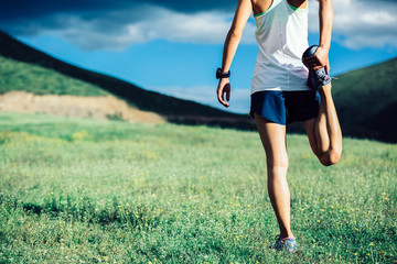 fitness woman trail runner warming up before running in mountains