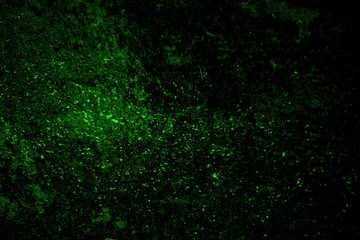 Abstract green background. Colored dust and powder explosion. Grainy particles texture isolated on black