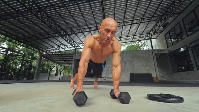 Fitness man making push ups exercises and lifting dumbbells for daily training