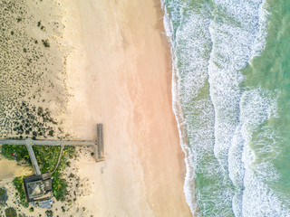 Fototapeta na wymiar Pier leading to sandy beach and waves in Quinta do Lago, Almancil, Algarve, Portugal