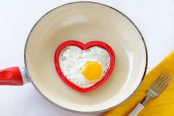 omelet from an egg in a frying pan in the shape of a heart