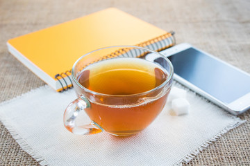 Morning cup of tea. Near the cup is a white smartphone.