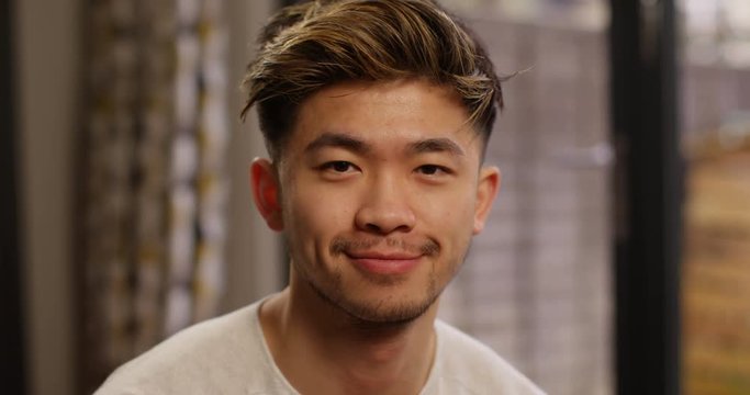 4K Close up portrait of young Asian man with friendly face smiling at camera