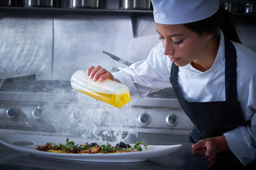 Chef woman working in kitchen with smoke