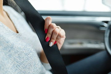 The woman's hand stretches behind the seat belt to fasten it.